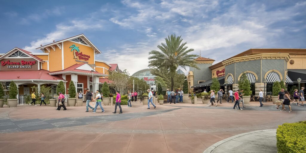 Wide exterior view of Westfield Brandon shopping center with storefronts including Bahama Breeze Island Grille; people walking around the outdoor plaza area.