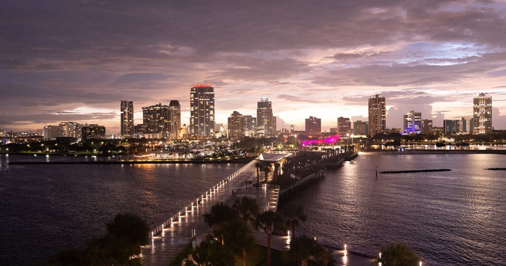 Twilight view of St. Petersburg, Florida skyline with the illuminated St. Petersburg Pier extending into the water.